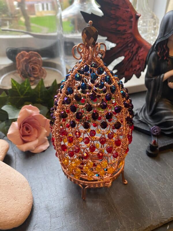 Hand-woven wire dragon’s egg with flame gradient beads, hinged decorative sculpture on cradle
